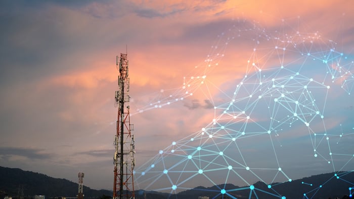 Telekommunikasjonsmast i solnedgang med digital nettverksvisualisering, som symboliserer sammenkoblet kritisk infrastruktur